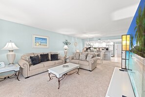 Ein Wohnzimmer mit einem beigefarbenen Sofa, einem weißen Couchtisch und einem Bild an der Wand.