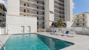 En swimmingpool med liggestole og en bygning med teksten 'Ocean Towers' i baggrunden.