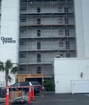 Ein mehrstöckiges Gebäude mit der Beschriftung 'Ocean Towers', einem Parkplatz und Gerüsten.