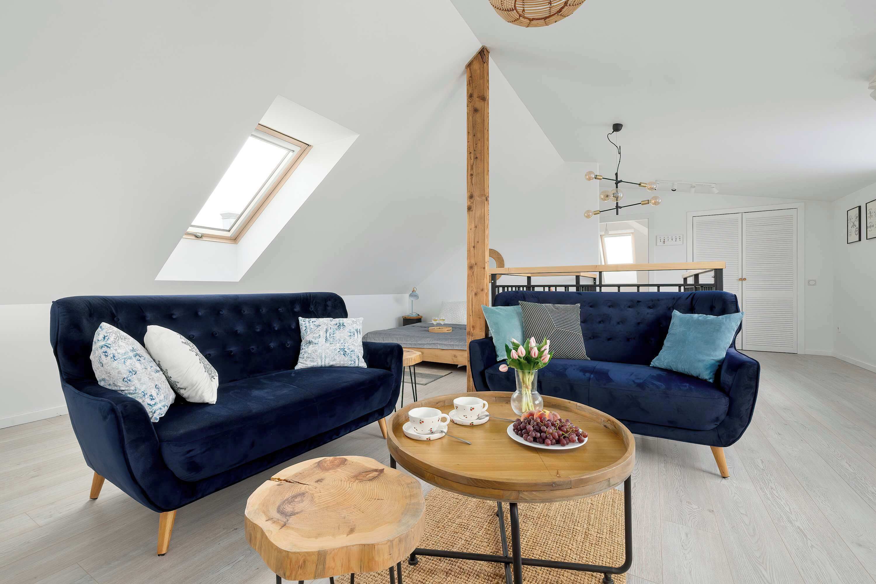 Bright and spacious living room with comfortable blue sofas, a coffee table, and plenty of natural light.