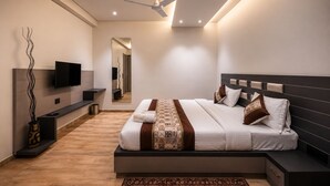 Quarto moderno com cama, mesas de cabeceira, televisão, ventilador de teto e espelho.