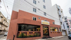Um hotel com fachada de tijolos, uma placa com a inscrição 'HOTEL GOLDSTAR' e uma entrada visível.