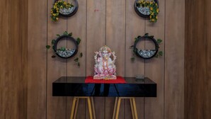 Um quarto com parede de painéis de madeira, uma mesa preta com tecido vermelho e uma estátua de divindade.