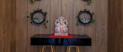 A room with a wooden panel wall, a black table with a red cloth, and a statue of a deity.