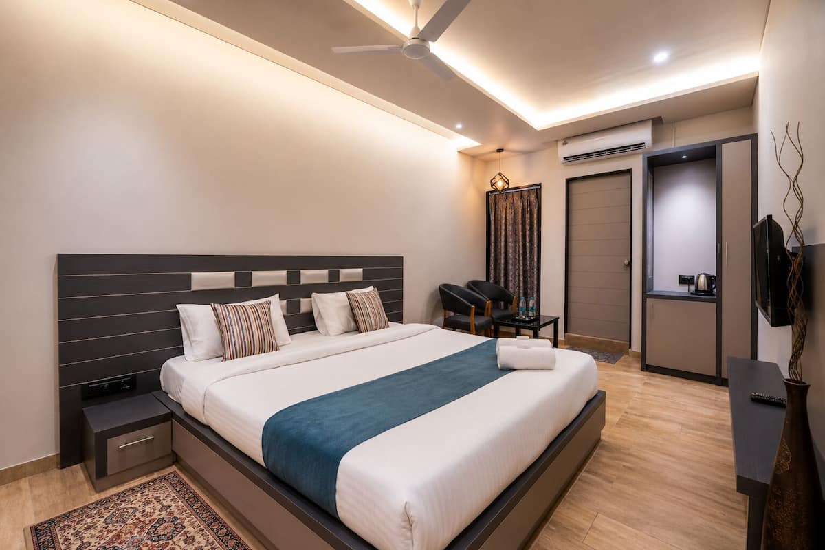 Una habitación de hotel moderna con una cama grande, mesitas de noche, un escritorio, una silla, un televisor y un ventilador de techo.