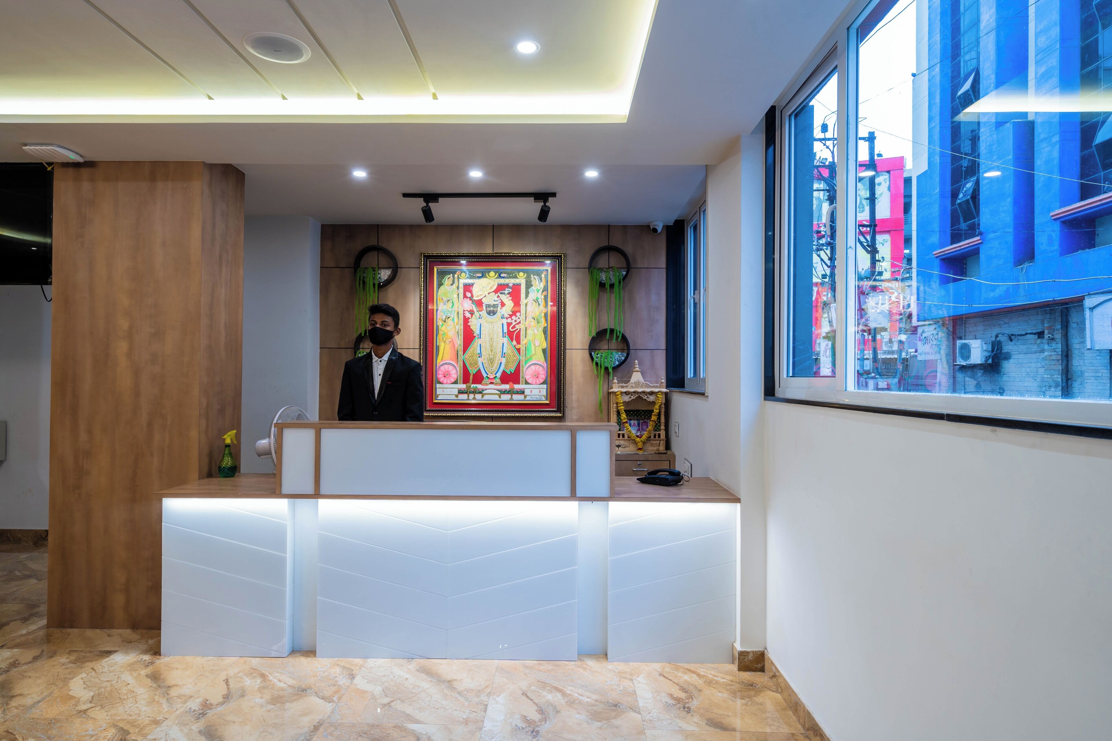 Una reception con un quadro incorniciato, un pilastro in legno e una finestra che si affaccia su edifici.