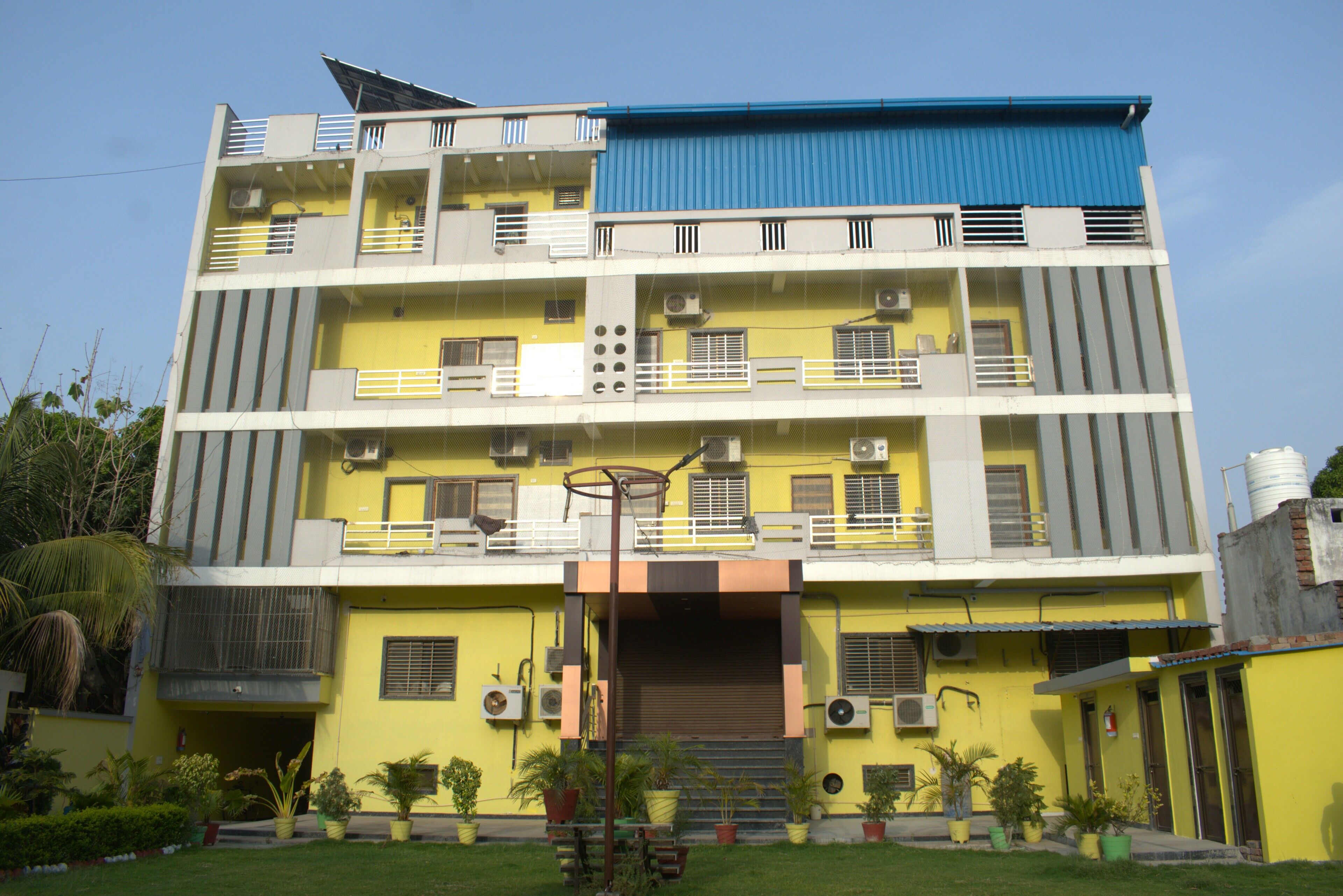 A multi-story building with balconies, air conditioning units, and a blue roof.