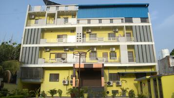 A multi-story building with balconies, air conditioning units, and a blue roof.