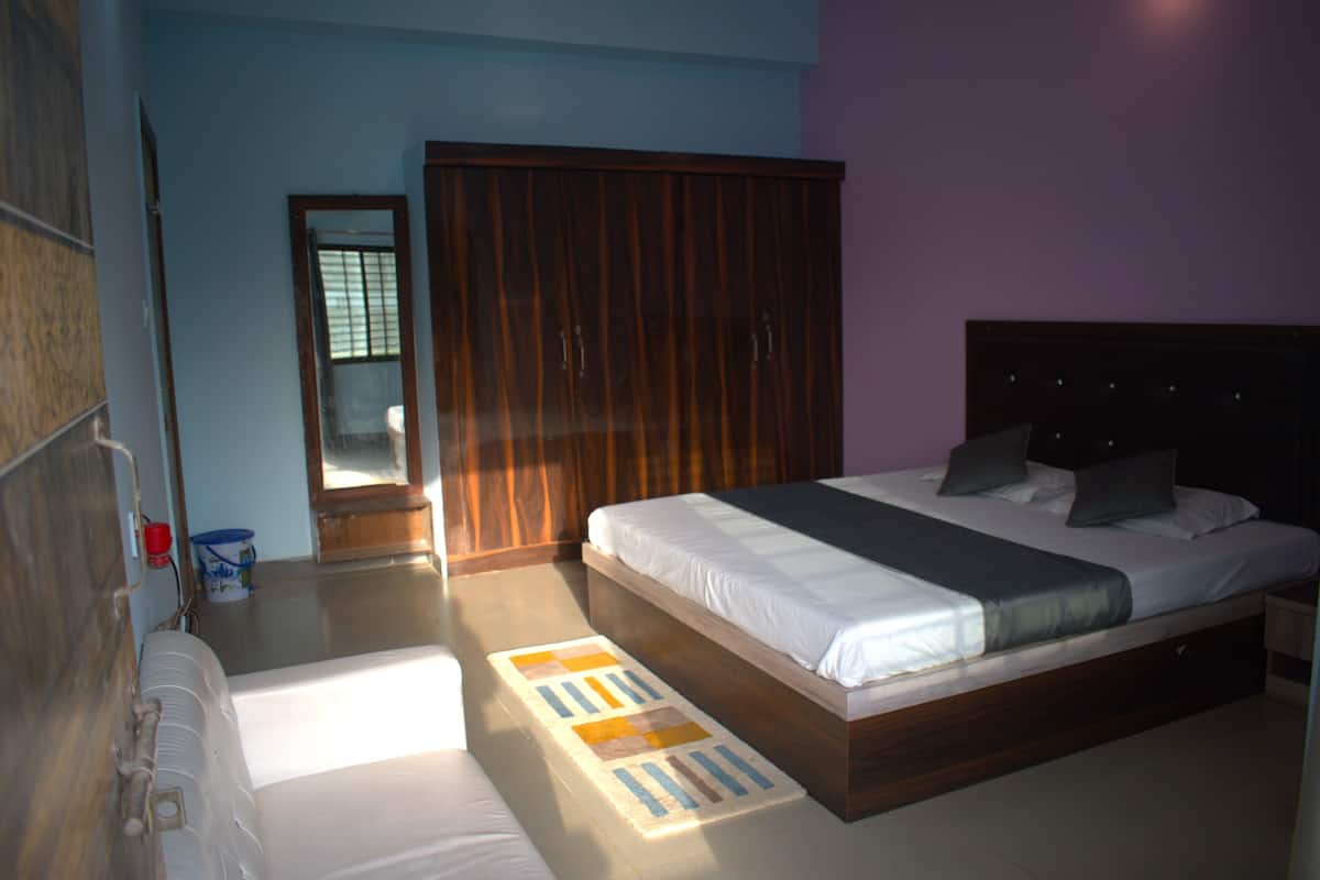 A bedroom with a bed, a wardrobe, a mirror, and a window.