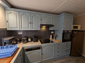 A kitchen with light blue cabinets, a microwave, a coffee maker, and a dishwasher. - Comfortable lodge in Vôge forest with WiFi and parking (Trémonzey)