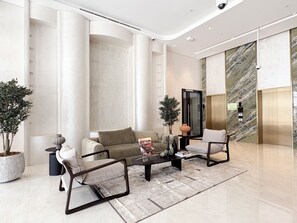 Un vestíbulo moderno con un sofá, sillones, una mesa de centro y una planta en maceta.
