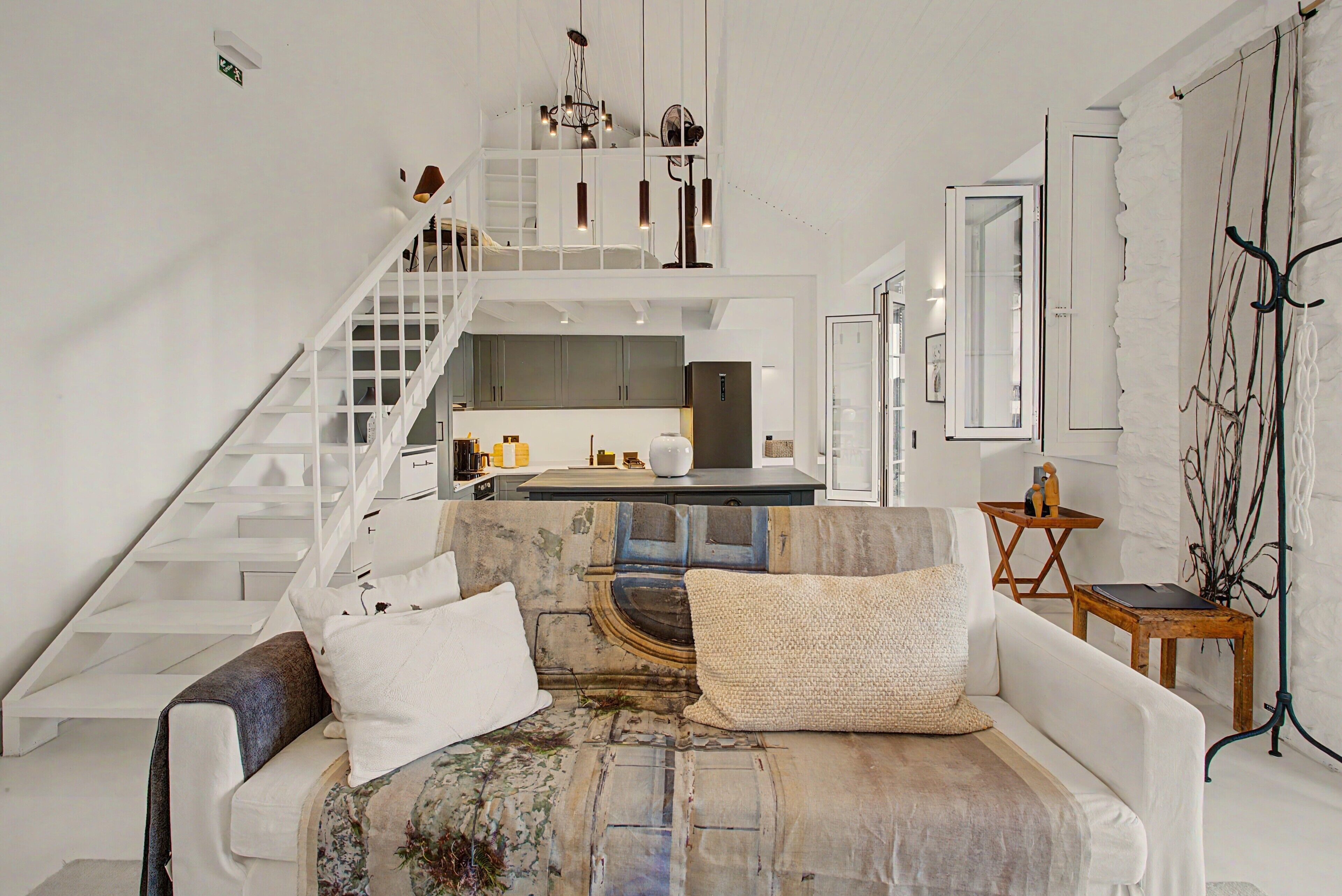 A modern interior with a staircase, a sofa, and a kitchen area.