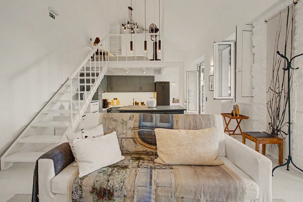 A modern interior with a staircase, a sofa, and a kitchen area.