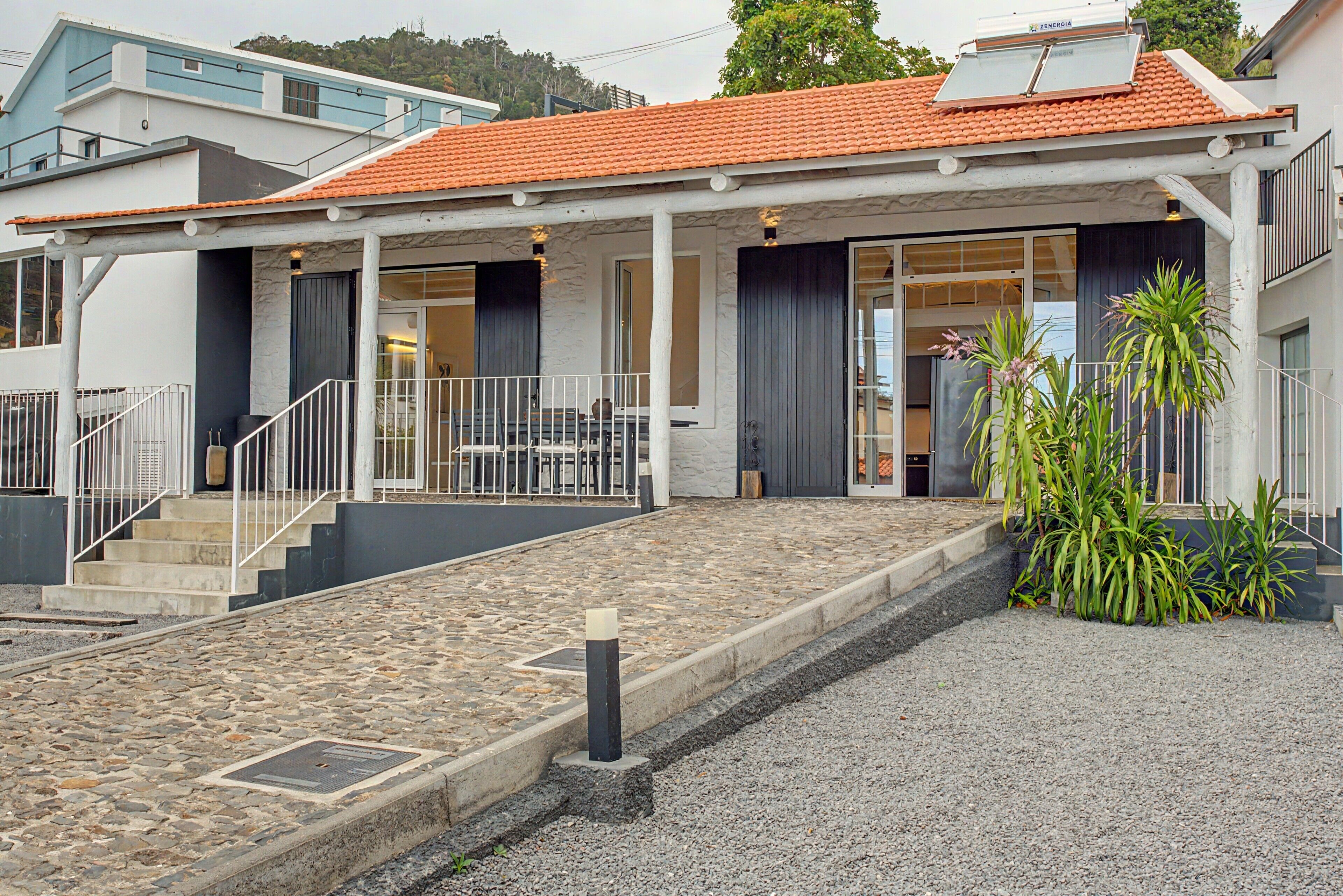 A building with a stone-paved entrance, a covered outdoor seating area, and a staircase leading to a second floor.