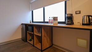 Una kitchenette compacta con ventana, cafetera y hervidor.