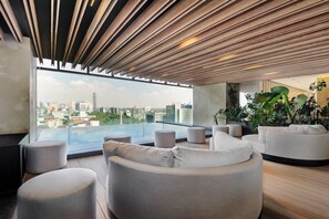 Eine moderne Dachterrasse mit Blick auf die Stadt, Holzdecke und bequemen Sitzgelegenheiten.
