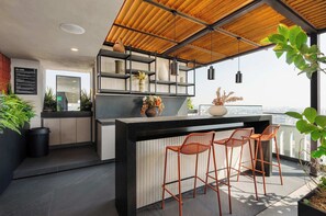 A modern kitchen with a bar area, wooden ceiling, and potted plants. - w Polished 1BR w Balcony in Tabacalera (Mexico City)