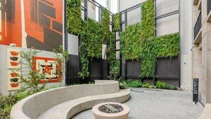 A courtyard with a circular seating area, a mural, and a wall covered in greenery. - w Polished 1BR w Balcony in Tabacalera (Mexico City)