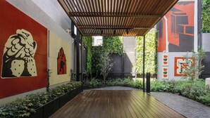 A wooden deck leading to a covered area with a modern design, surrounded by greenery and art on the walls. - w Enchanting Loft w Balcony in Tabacalera (Mexico City)