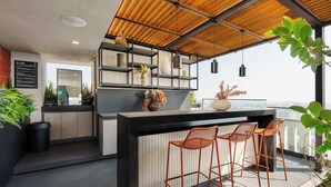 A modern kitchen with a bar area, wooden ceiling, and potted plants. - w Enchanting Loft w Balcony in Tabacalera (Mexico City)