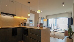 Eine moderne Küche mit integrierten Geräten, ein Essbereich mit Tisch und Stühlen sowie ein Balkon mit Blick.