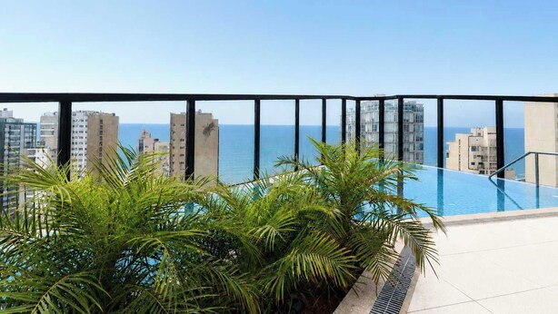 Ein Pool auf dem Dach mit Blick auf das Meer und die Gebäude.