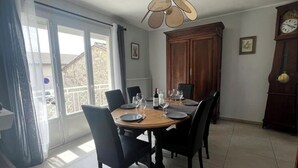 Een eethoek met een ronde tafel voor vier personen, stoelen, een houten kast en een wandklok.