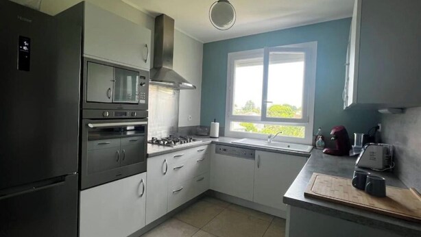 Een keuken met een fornuis, oven, magnetron en vaatwasser.