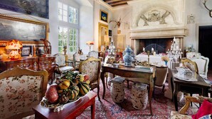 A traditional room with a fireplace, antique furniture, and a large painting.