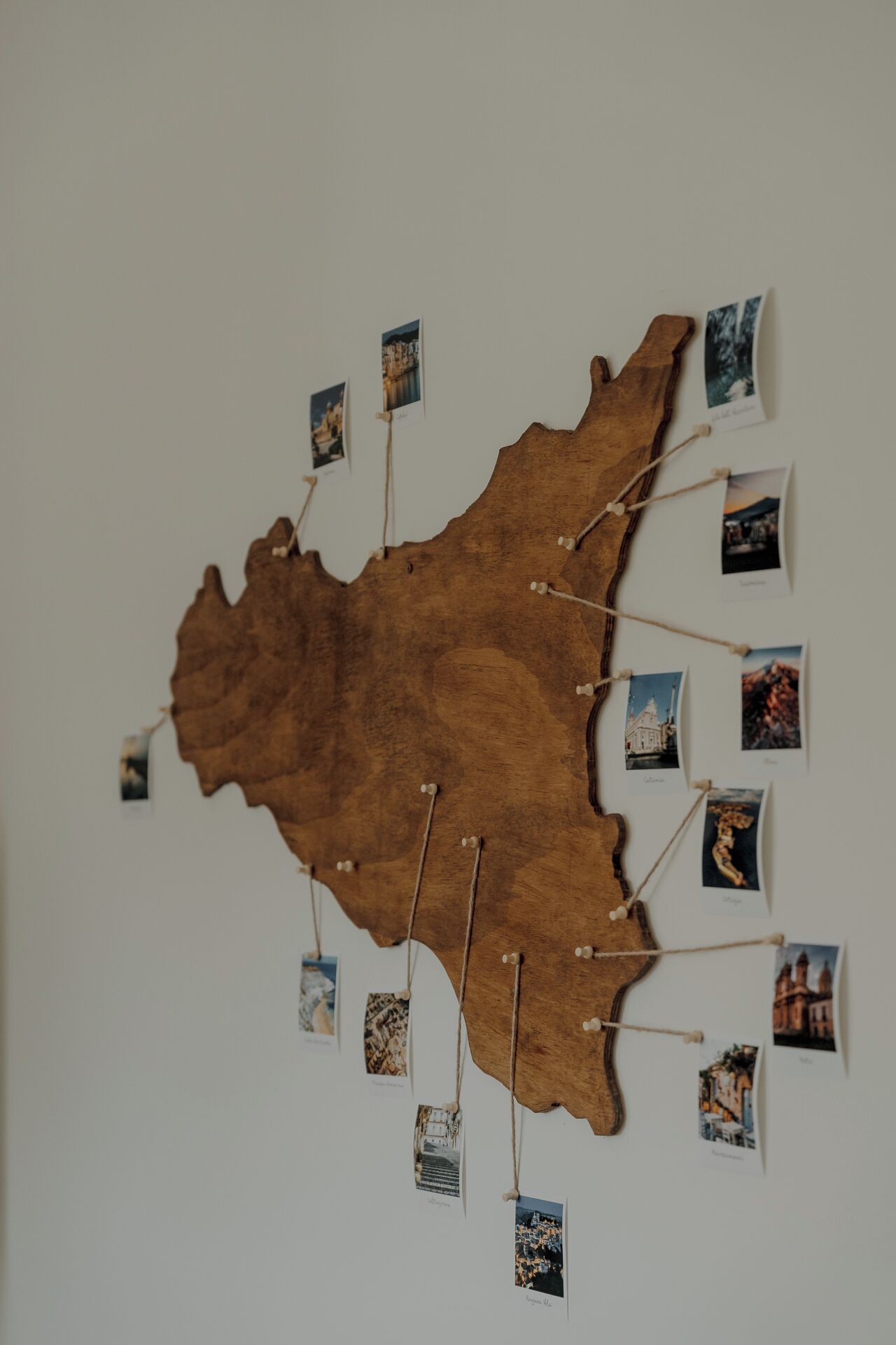 Une carte en bois fixée au mur, sur laquelle sont accrochées des photos.