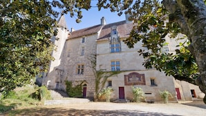A historic stone building with a central tower, a covered staircase, and a courtyard.