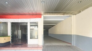 An entrance with a red awning, glass doors, and a tiled floor leading to a corridor. - Family Luxury Suite W/free Wifi and Parking (Makassar)