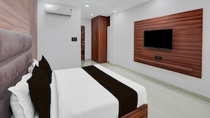 Quarto de hotel com uma cama, televisão na parede, guarda-roupa e ar condicionado.