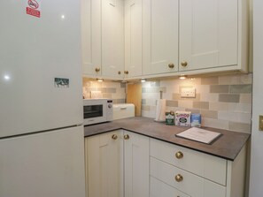 A kitchen with white cabinets, a Bosch microwave, and a coffee machine. - Throstlegarth (Milnthorpe)
