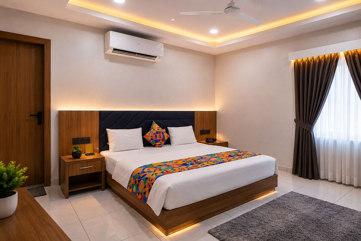 A modern hotel room with a large bed, bedside tables, an air conditioning unit, a ceiling fan, and a window with curtains.