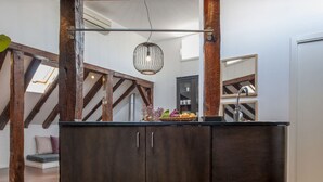 Une cuisine avec des meubles de rangement en bois foncé, un luminaire suspendu et une vue sur un escalier.