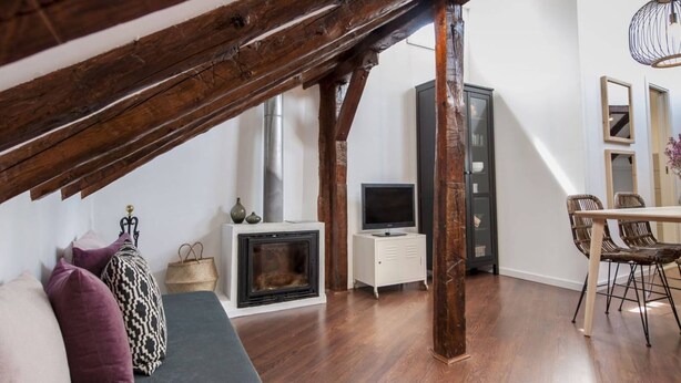 Un salon de style industriel, avec une cheminée, un téléviseur, un coin repas et un escalier.