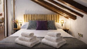 Une chambre d’hôtel avec un lit, deux tables de chevet, un plafond en bois et une vue sur l’extérieur.
