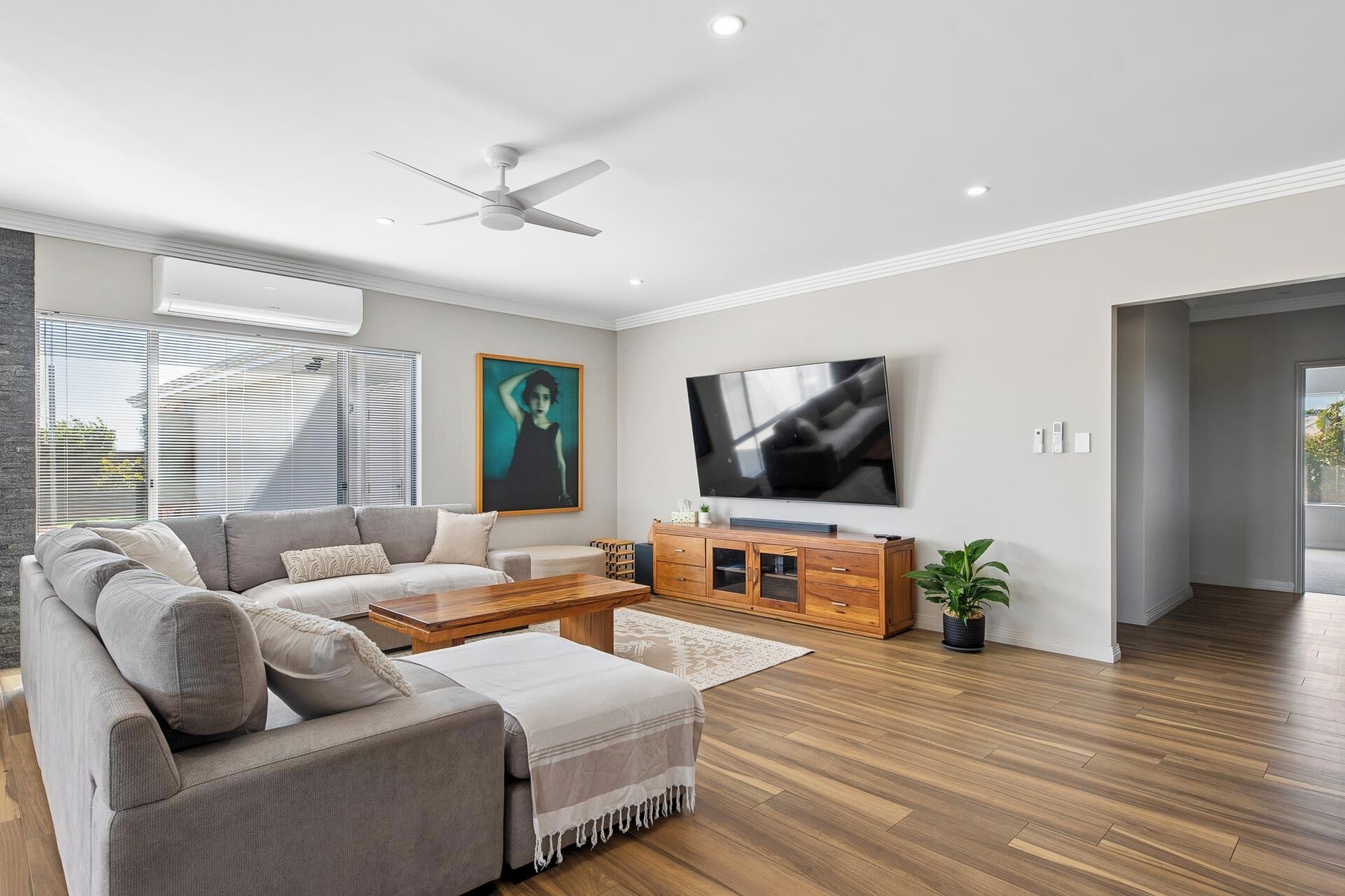 A modern living room with a sofa, coffee table, TV, and ceiling fan.