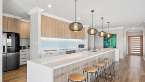 A modern kitchen with a central island, bar stools, and pendant lighting.