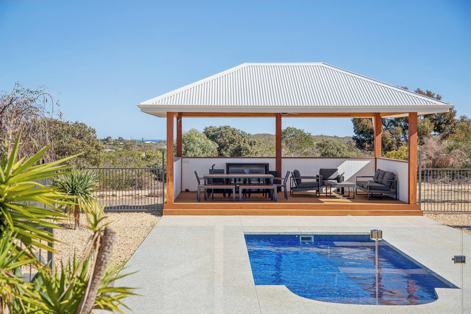 A covered outdoor area with a pool, a barbecue, and seating.