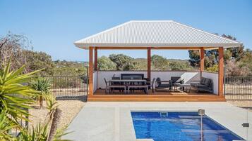 A covered outdoor area with a pool, a barbecue, and seating.