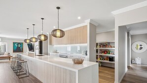 A modern kitchen with a central island, pendant lighting, and a built-in bookshelf.
