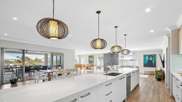 A modern kitchen with white cabinetry, a large island, and pendant lighting.