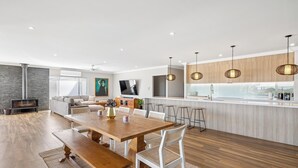 A modern kitchen with a central island, wooden flooring, and pendant lighting.