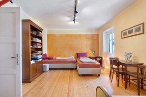 A compact room with two beds, a wooden wardrobe, a desk with a chair, and a window. - Apartment 'Casa Avisio' with Private Garden, Wi-Fi and Ski Slopes Nearby (Castello-Molina di Fiemme)
