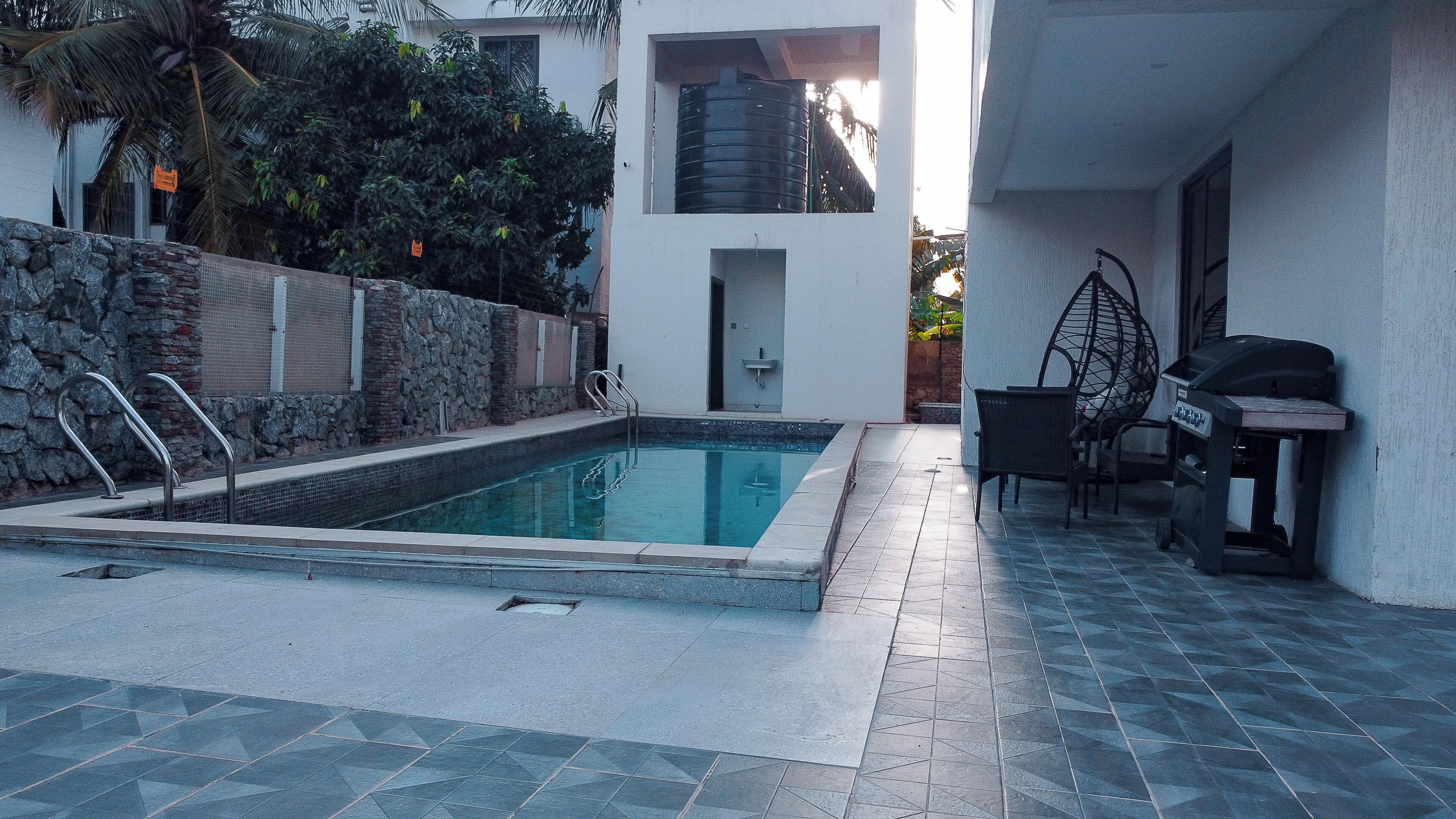 Una piscina con muro de piedra y zona de barbacoa.
