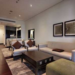 A modern living room with a sofa, armchairs, a coffee table, and a kitchen in the background. - Luxury 2BR at Anantara Palm Beach & Pool Access (Dubai)