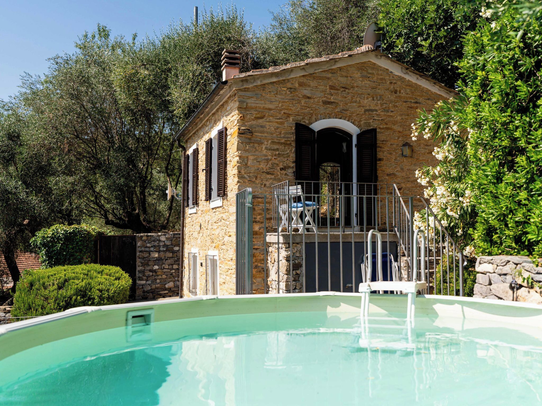 A stone building with a pool, surrounded by greenery.