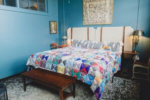 A bedroom with a large bed, a wooden bench, a nightstand, a lamp, and a wall hanging. - HISTORIC 1945 SCHOOLHOUSE. 4700 sq. ft. of luxury five minutes from Lake Fork. (Como)